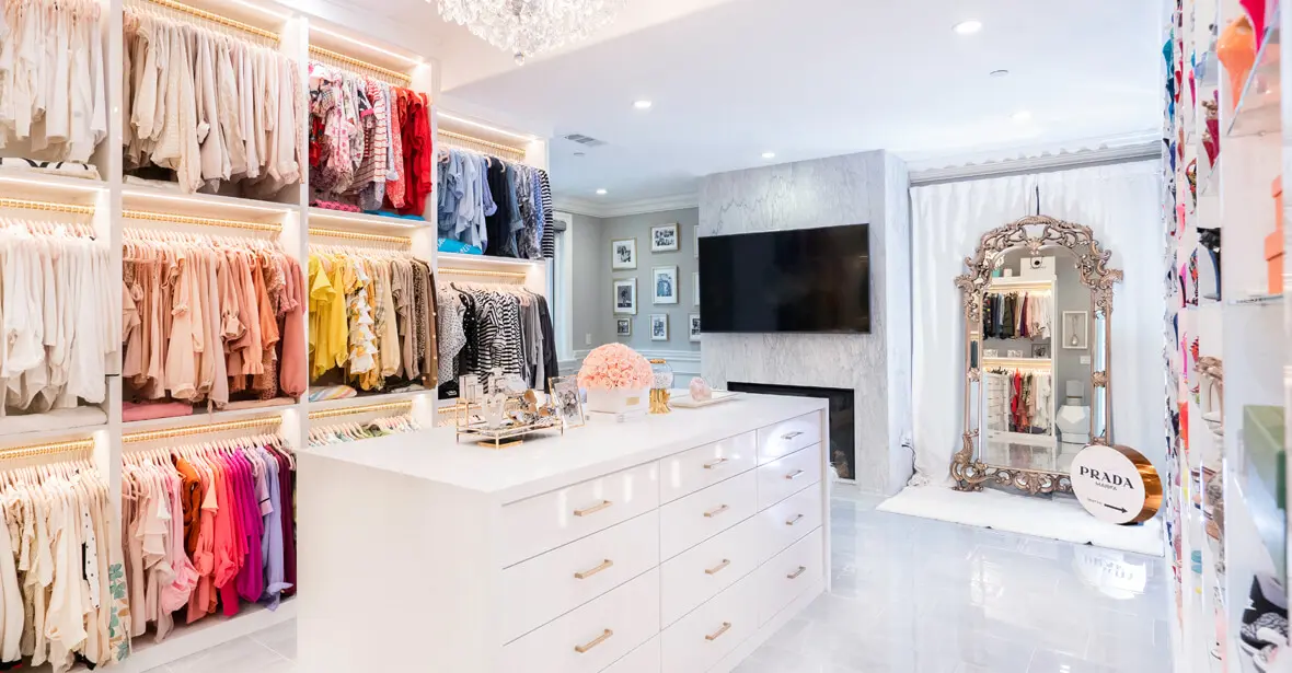 A bright, luxury custom dressing room with a marble fireplace and gold-accent island.