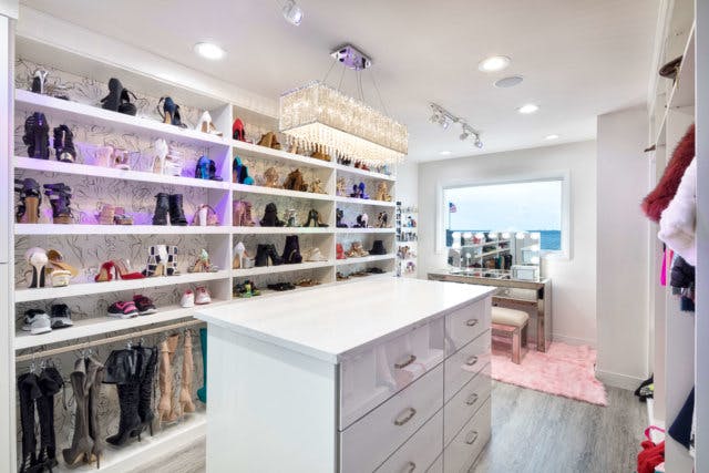 A boutique closet with integrated LED shoe walls and a chandelier.